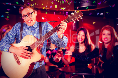 Composite image of geeky hipster playing the guitar