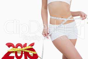 Composite image of midsection of slim woman measuring waist