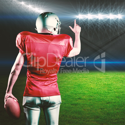 Composite image of rear view of american football player pointing while holding ball