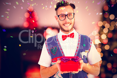 Composite image of geeky hipster offering christmas gift