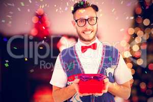 Composite image of geeky hipster offering christmas gift