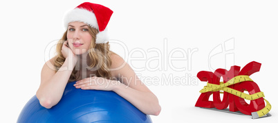 Composite image of festive fit blonde leaning on exercise ball