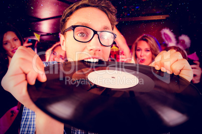 Composite image of geeky hipster biting vinyl record