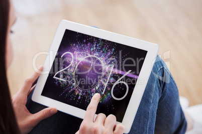 Composite image of teen using a tablet pc sitting on the floor