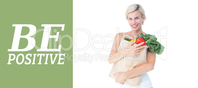 Composite image of attractive woman holding bag of vegetables