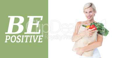 Composite image of attractive woman holding bag of vegetables