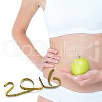 Composite image of woman holding an apple in front of her belly