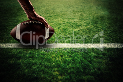 Composite image of american football player holding ball