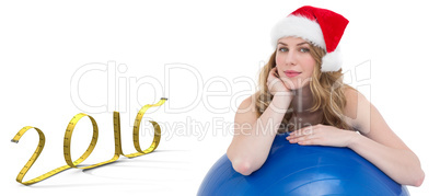 Composite image of festive fit blonde leaning on exercise ball