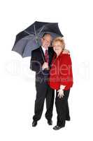 Senior couple standing with umbrella.