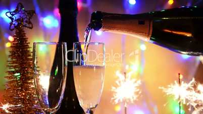 Champagne is poured into glasses on a background of Bengal lights