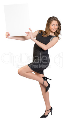 Young girl is holding a big empty billboard, standing on one leg