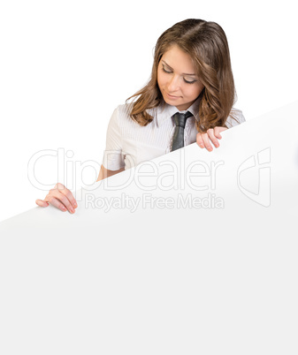 Young girl in tie looking down at a large blank poster