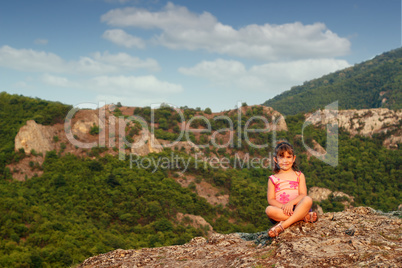 beautiful little girl sitting on mountain top