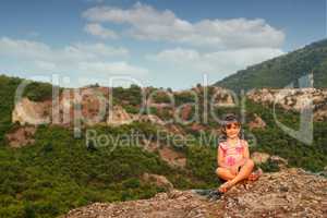 beautiful little girl sitting on mountain top