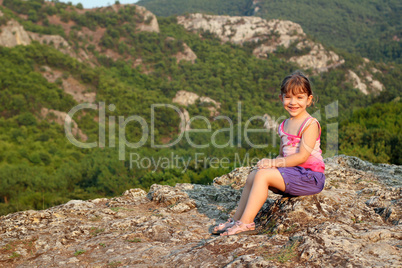 happy little girl sitting on mountain top