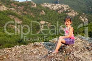 happy little girl sitting on mountain top