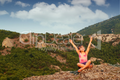 happy little girl with hands up on mountain top
