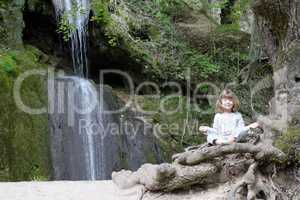 little girl meditate by the waterfall