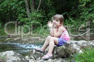 little girl sitting next to a stream