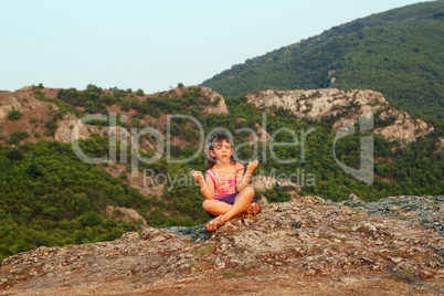 little girl sitting on a mountain top and meditate