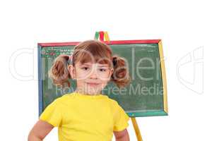 little girl standing in front of a drawing board