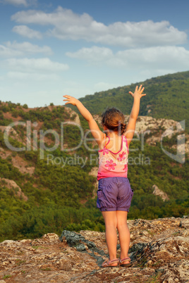 little girl standing on mountain peak