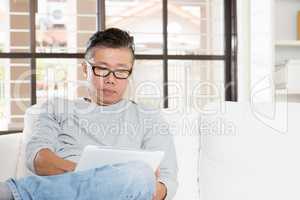 Mature Asian man using tablet computer