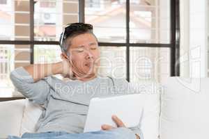 Mature Asian man neck pain while using tablet computer