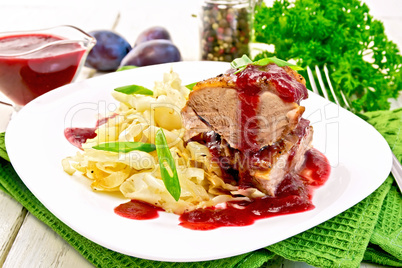 Duck breast whole with plum sauce and cabbage in plate on napkin