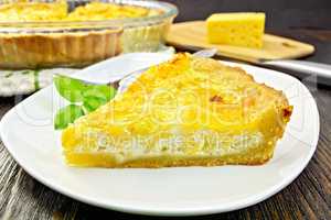 Pie with cheese and leeks in plate on dark board