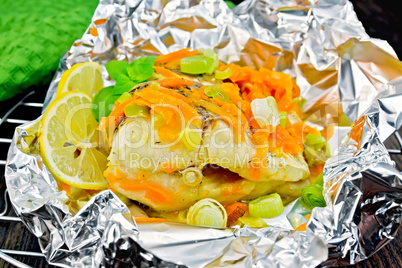 Pike with carrots and leeks in foil on board