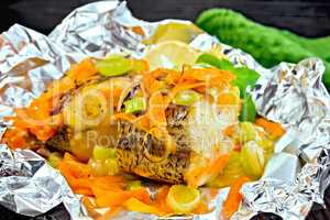 Pike with carrots and onions in foil on board