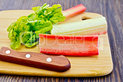 Rhubarb with knife and leaf on board