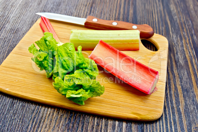 Rhubarb with knife and leaf on dark board