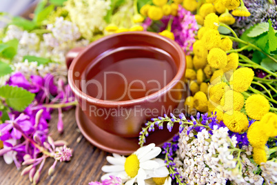 Tea from wild flowers in clay cup on board