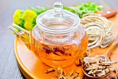 Tea of Rhodiola rosea in glass teapot on tray with spoon