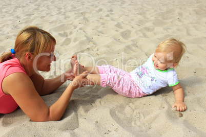 mother plays with her baby plays on the sand