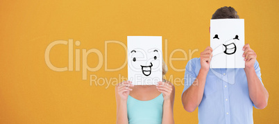 Composite image of young couple holding pages over their faces