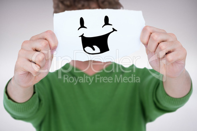 Composite image of man holding blank paper in front on face