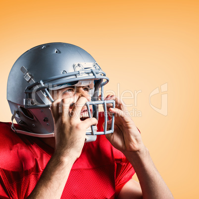 Composite image of aggressive american football player holding h