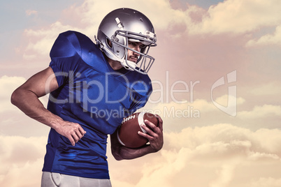 Composite image of american football player holding ball in mid-