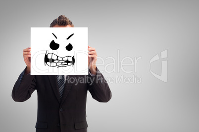 Composite image of businessman holding a white card in front of