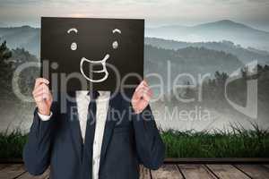 Composite image of businessman holding board