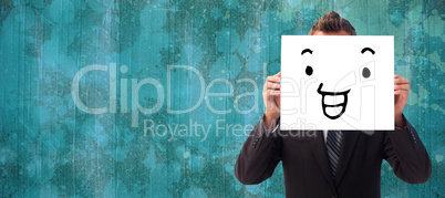 Composite image of businessman holding a white card in front of