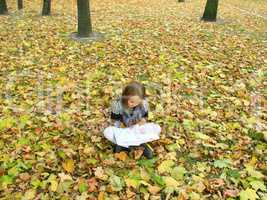 young girl reads a book in the autumn park