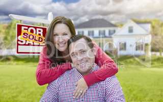 Couple In Front of Sold For Sale Sign and House