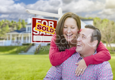 Couple In Front of Sold For Sale Sign and House