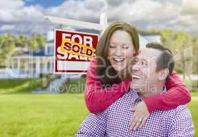 Couple In Front of Sold For Sale Sign and House