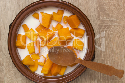 Pumpkin sliced in clay pot with milk